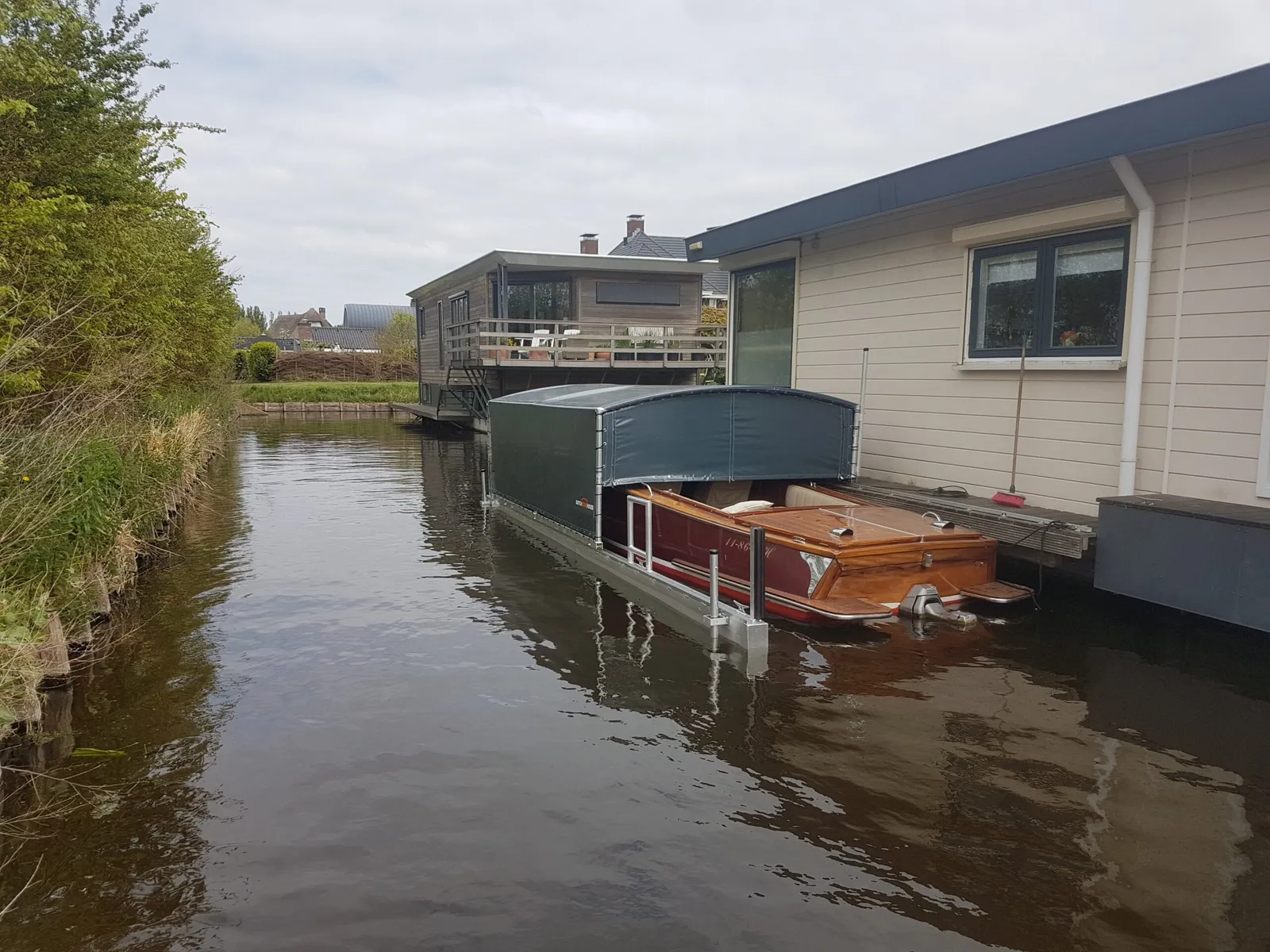 Houten boot onder een geopende bootoverkapping in een vaart