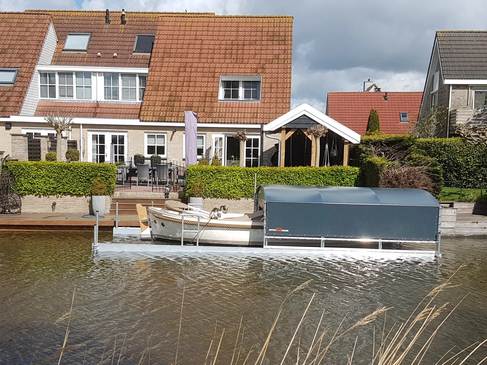 Sloep naast een bootoverkapping in een woonwijk aan het water