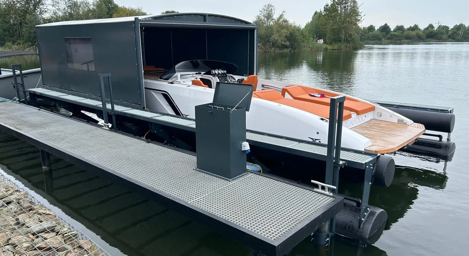 Motorboot op een drijvende bootlift onder een geopende grijze bootoverkapping