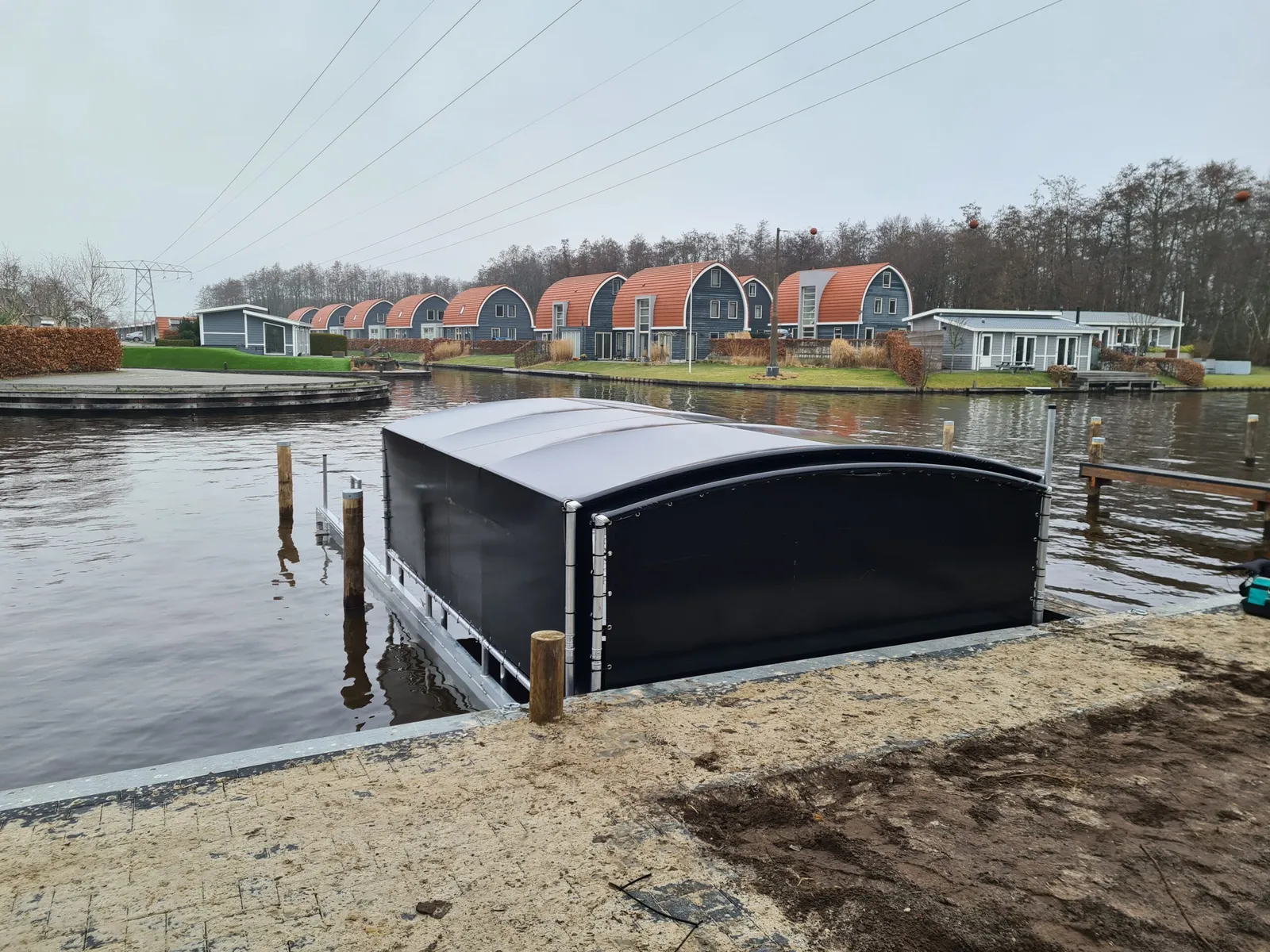Zwarte bootoverkapping aan een nieuw aangelegde oever