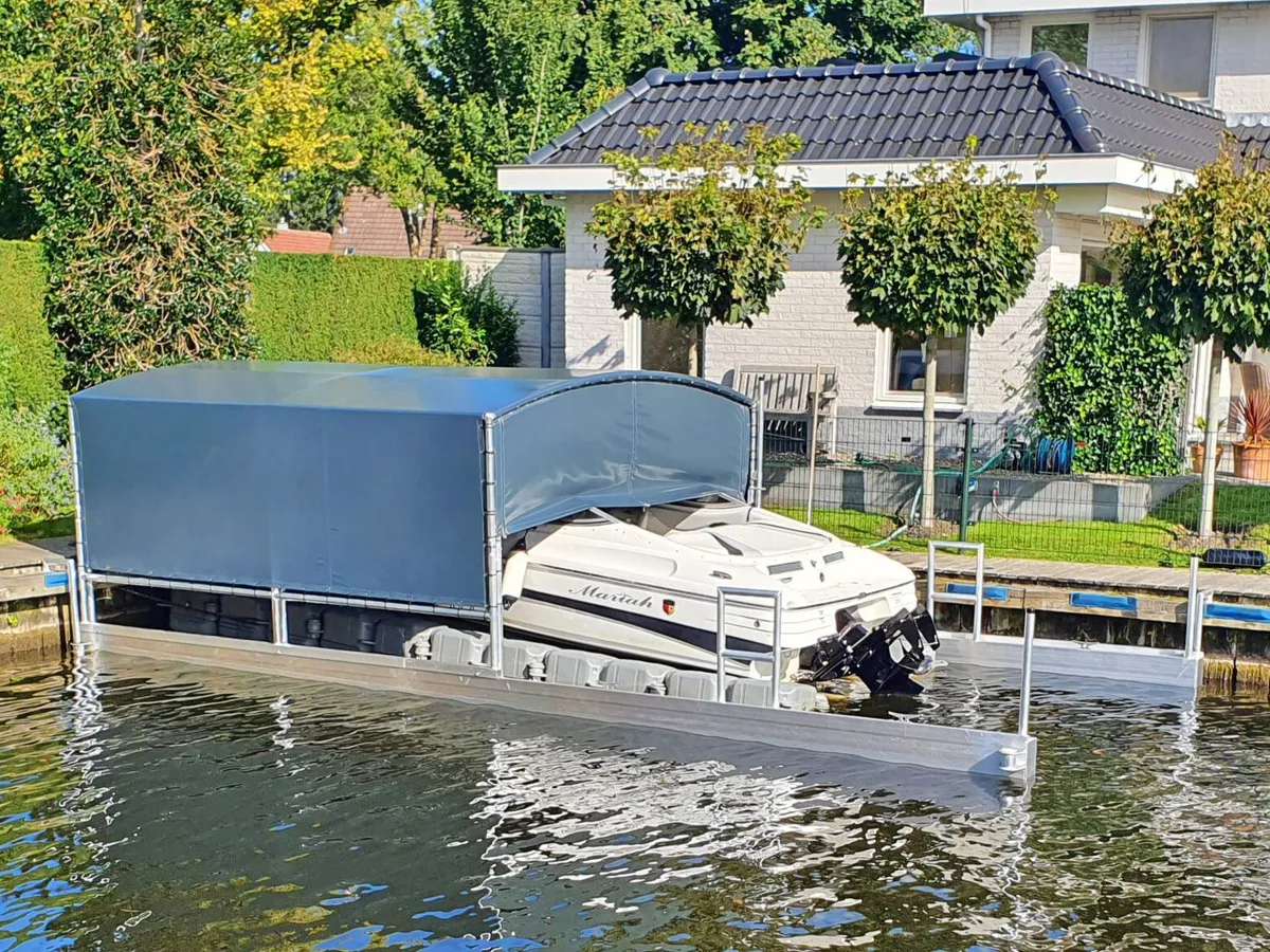 Motorboot onder een geopende drijvende bootoverkapping bij een tuin