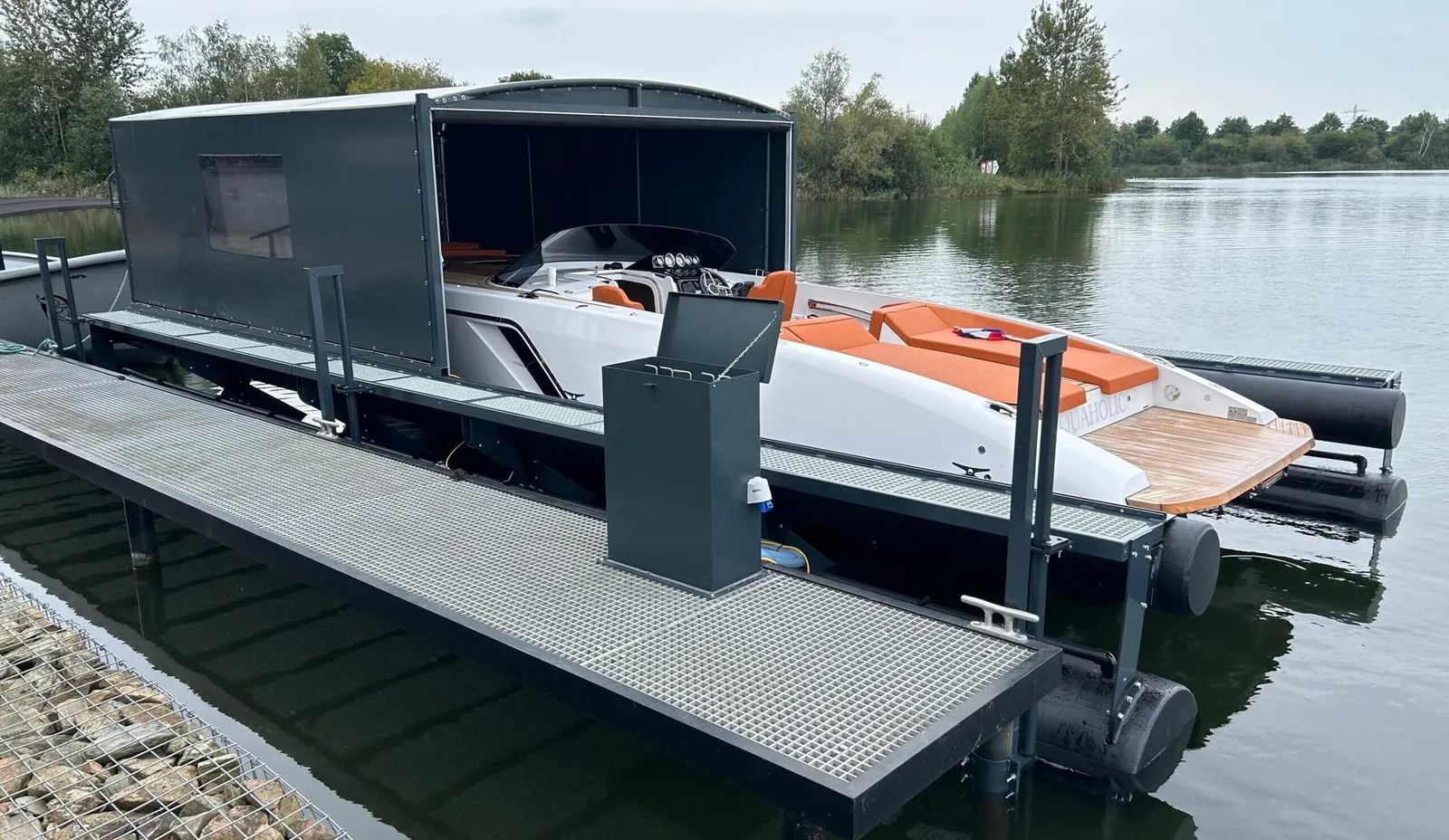 Motorboot auf einem schwimmenden Bootslift unter einer geöffneten grauen Bootsüberdachung
