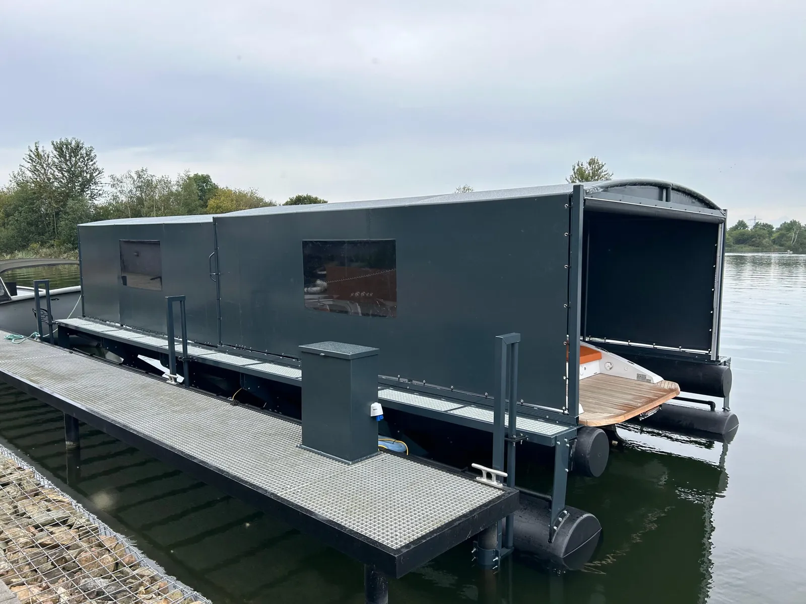 Gesloten bootoverkapping met ramen op een drijvende bootlift langs een loopsteiger