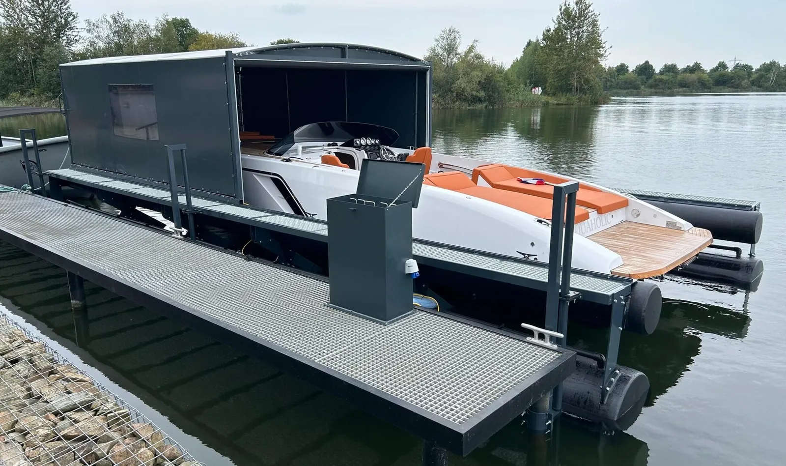 Motorboat on a floating boat lift under an opened grey boat shelter