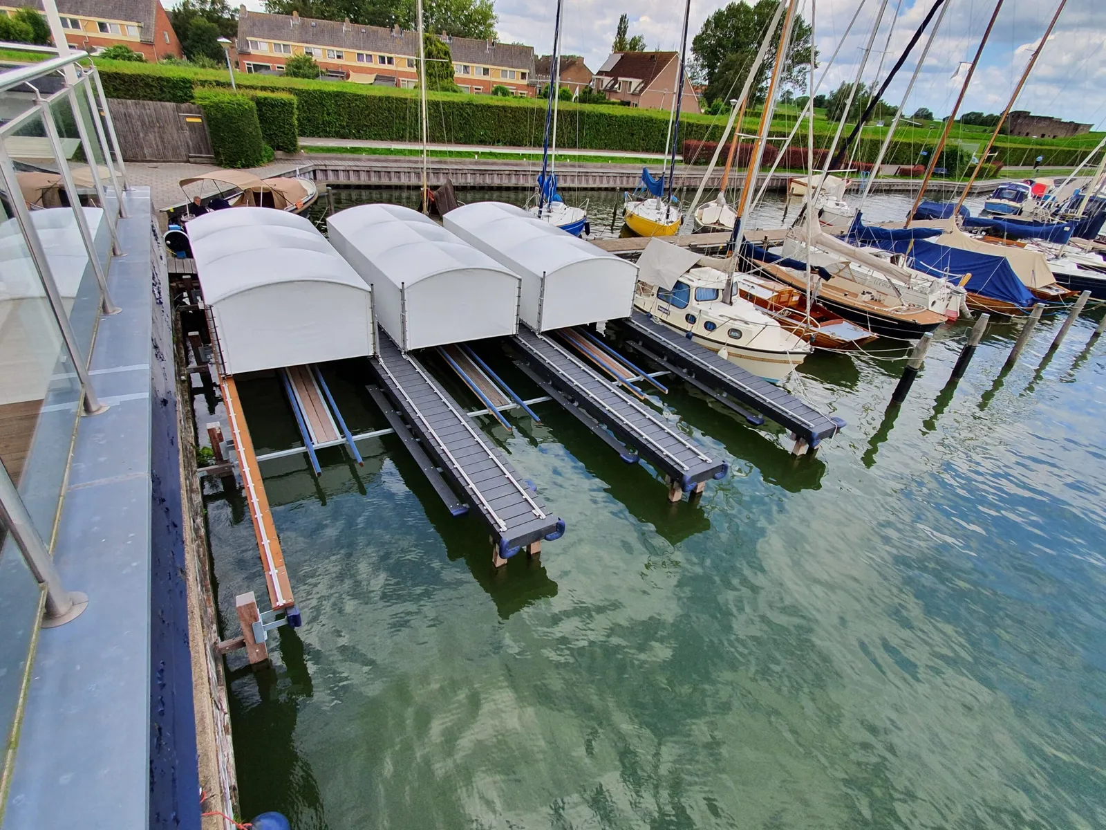 Witte bootoverkappingen boven ligplaatsen in een jachthaven