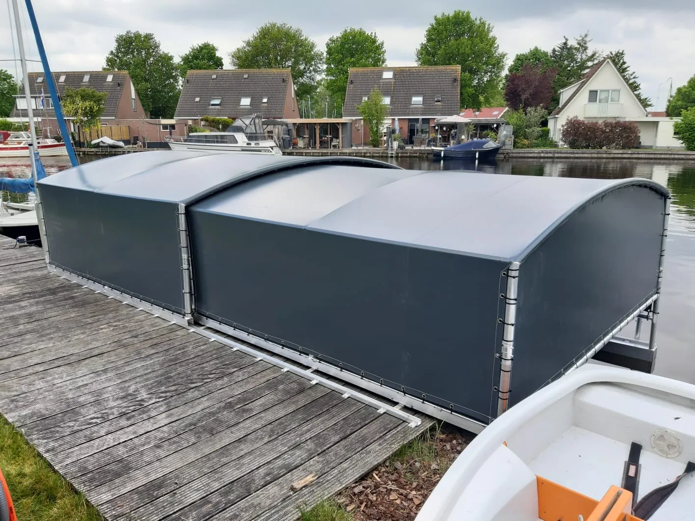 Bootoverkapping uit twee delen langs een steiger in een woonwijk